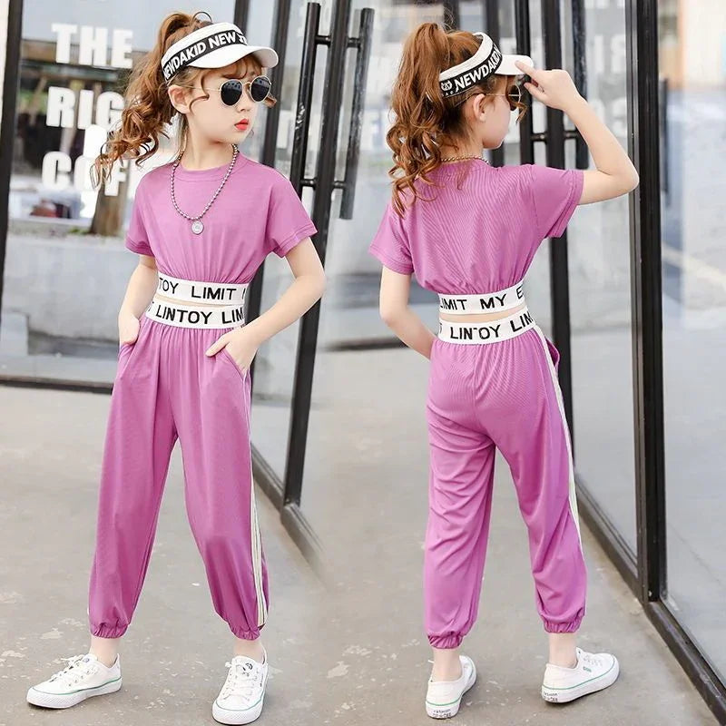Girl wearing loose-fit pink jumpsuit with short sleeves, elastic waistband, and white side stripes