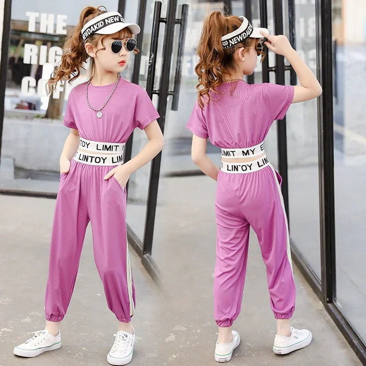 Girl wearing loose-fit pink jumpsuit with short sleeves, elastic waistband, and white side stripes