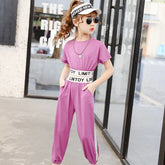 Girl wearing a pink short-sleeve jumpsuit with elastic waistband and white stripe detail.