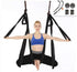 Woman wearing a blue sports bra and black leggings, demonstrating aerial yoga with a black hammock swing.