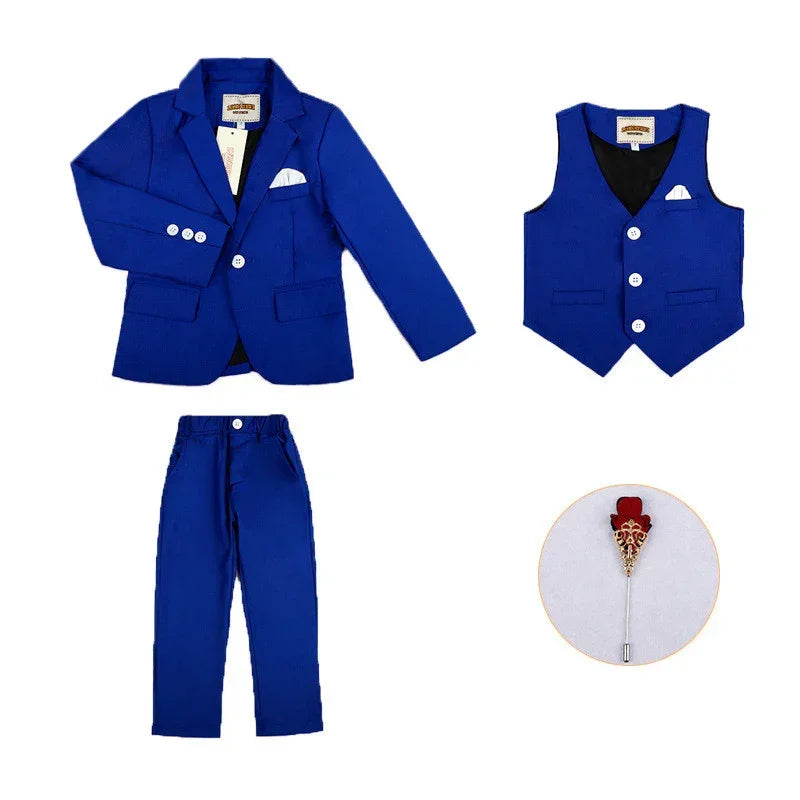 Four-piece boys' suit set with blue blazer, vest, trousers, and decorative pin, slim fit.