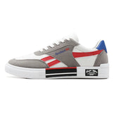 White low-top sneaker with grey suede overlays, red accents, blue heel, and chunky sole
