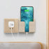 Beige wall-mounted phone holder with charging smartphone, minimal modern design.