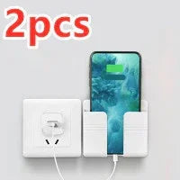 Wall-mounted white plastic phone holder with charging slot, shown with smartphone and outlet