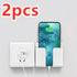 Wall-mounted white plastic phone holder with charging slot, shown with smartphone and outlet