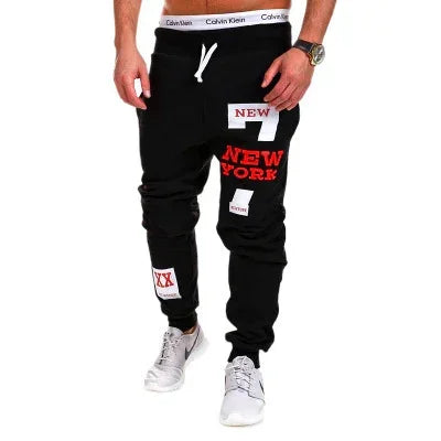 Black jogger pants with red and white New York graphic patches, slim fit streetwear style