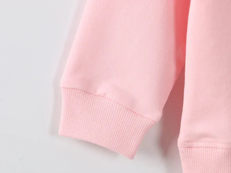 Close-up of light pink cotton sweatshirt sleeve with ribbed cuff, relaxed fit.