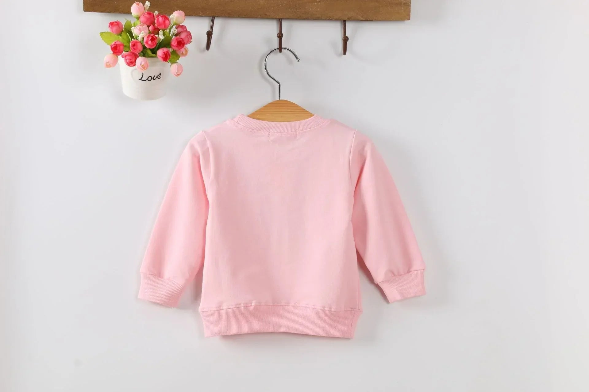 Light pink cotton pullover sweatshirt with long sleeves and ribbed cuffs, relaxed fit