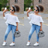 Girl in off-shoulder white lace top, blue skinny jeans with pearl details, and white sneakers