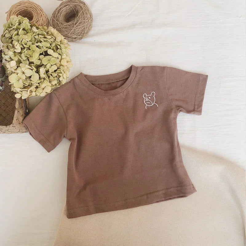 Brown cotton short sleeve t-shirt with bear graphic, relaxed fit, laid flat on fabric.