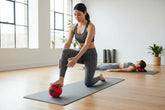 Woman in gray seamless sports bra and leggings doing yoga on mat, fitted activewear set