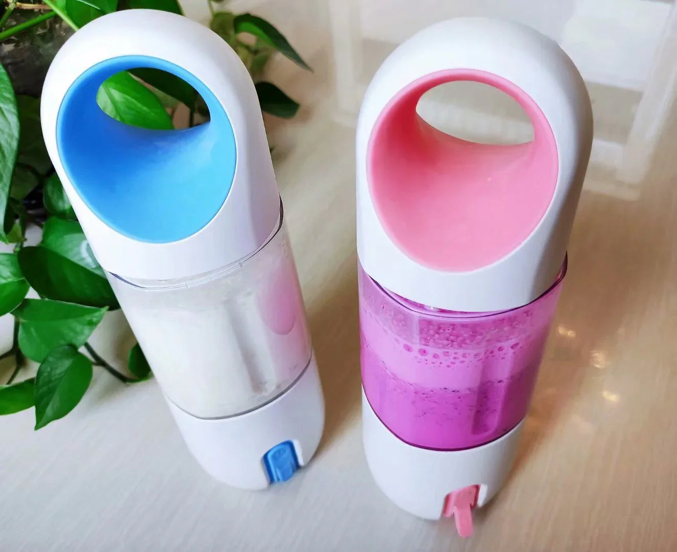 Two portable plastic drink bottles with pastel blue and pink accents and handles, modern design