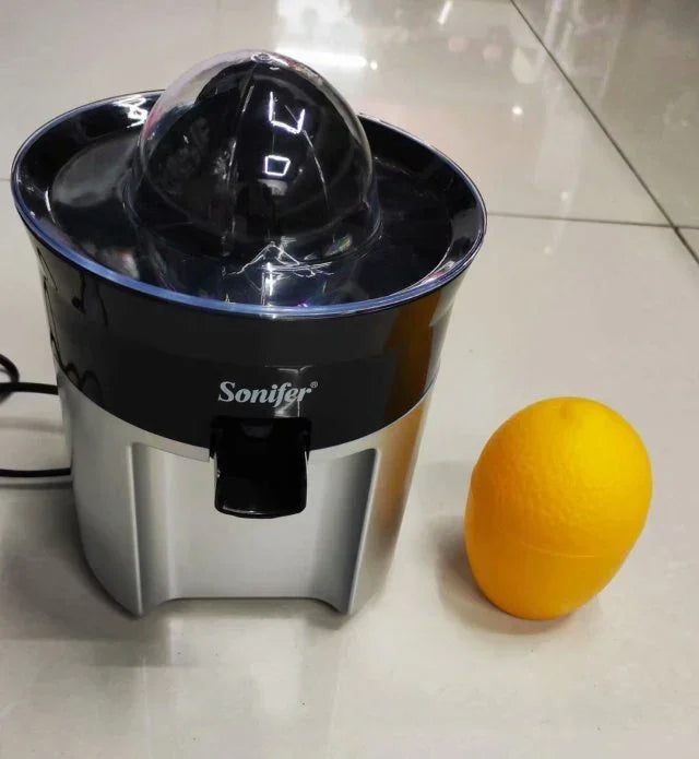 Electric citrus juicer with stainless steel finish next to a whole orange on tile floor
