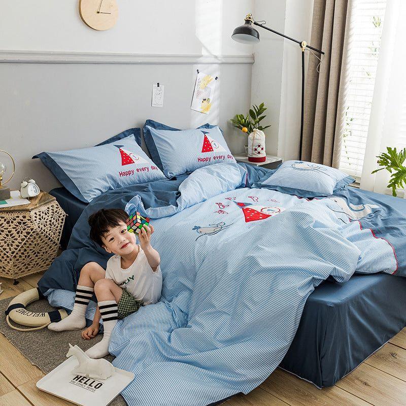 Child sitting on a bed with blue striped bedding featuring playful cartoon prints and relaxed fit.