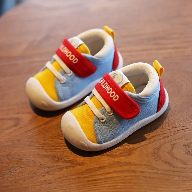 Colorful baby sneakers with blue and yellow fabric, red velcro strap, and white soles