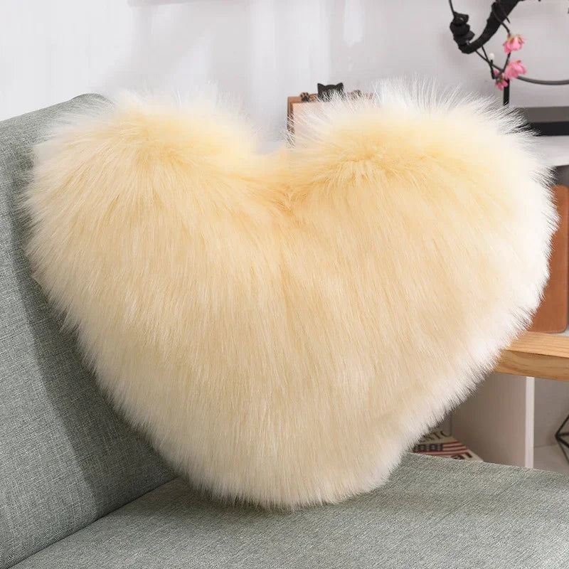 Fluffy heart-shaped cream faux fur pillow on grey sofa, cozy home decor accent
