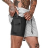 Black compression shorts with side pocket under light gray athletic shorts, worn for gym or streetwear style
