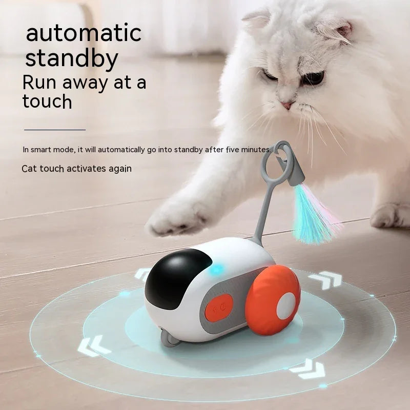 White fluffy cat playing with interactive automatic moving cat toy with colorful feather attachment on wooden floor.