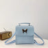 Light blue faux leather crossbody bag with butterfly metal detail and top handle