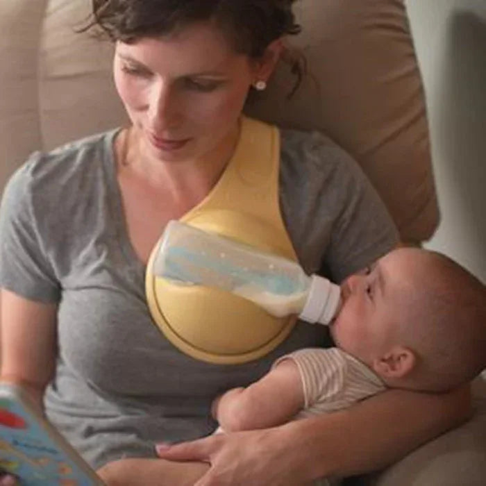 Woman wearing gray short-sleeve top using yellow hands-free baby bottle holder, feeding baby