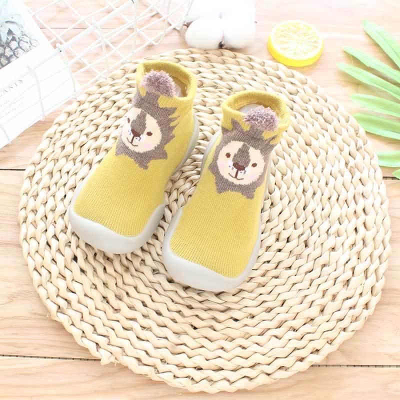 Yellow knit toddler sock shoes with lion face pattern and flexible rubber sole, slip-on fit