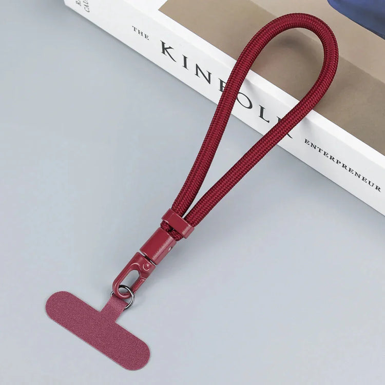 Maroon nylon wrist strap with metal clasp, minimalist design, tech accessory on table