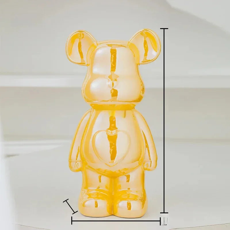 Shiny yellow bear figurine with heart detail, measuring height and width on white background.