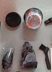 Assorted black and silver grooming tool attachments and cleaning brush on a light surface