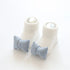 White ribbed knit baby socks with blue gingham bow accents, soft and snug fit.