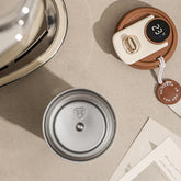 Flat lay of modern tech accessories, round metal lid, and minimalist gadgets on beige surface