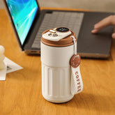 White insulated travel mug with brown lid, digital temperature display, textured grip.