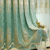 Light teal velvet curtain with gold embroidered patterns and scalloped edge, draped beside a gold decorative elephant figurine.