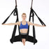 Woman in blue sports bra and black leggings doing aerial yoga in black hammock