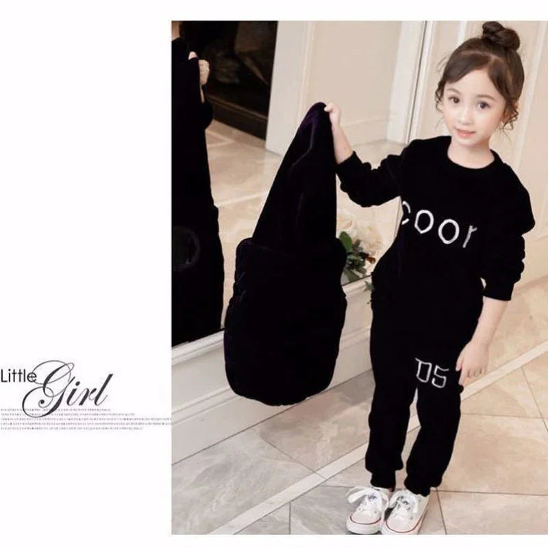 Little girl in black velvet matching sweatshirt and jogger pants set with white sneakers