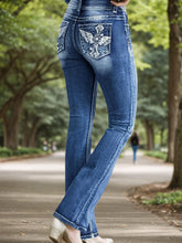 Woman wearing blue flared denim jeans with embroidered back pockets, standing outdoors.