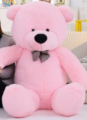 Large plush pink teddy bear with black bow tie, soft fuzzy fabric, sitting upright indoors