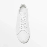 Minimalist white leather sneaker with lace-up design and low-top fit on white background