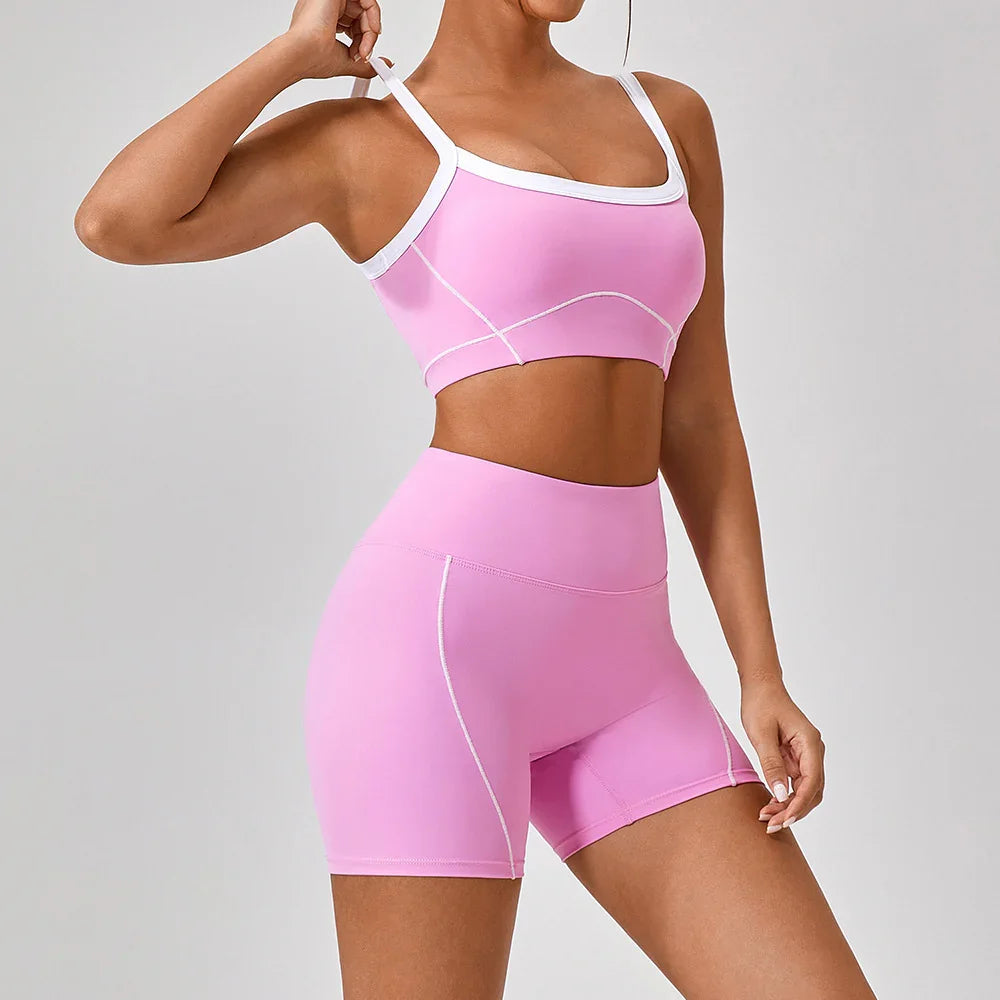 Woman wearing fitted pink athletic crop top and high-waisted shorts with white trim
