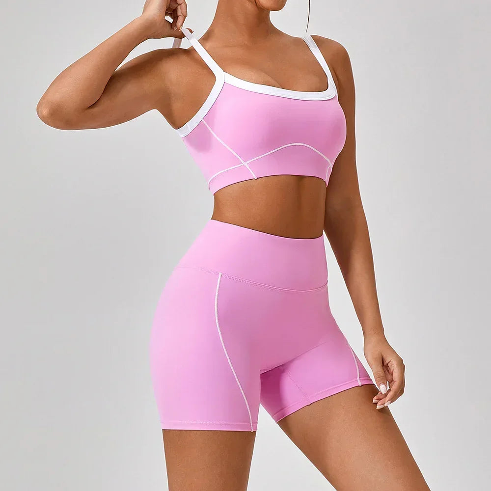 Woman wearing fitted pink athletic crop top and high-waisted shorts with white trim