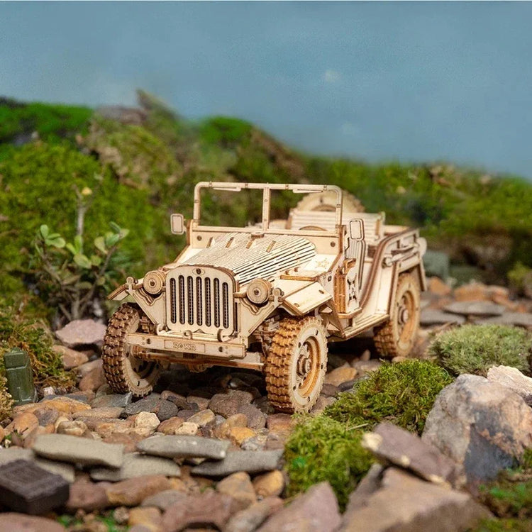 Wooden model jeep on rocky terrain with greenery, detailed vintage vehicle design.