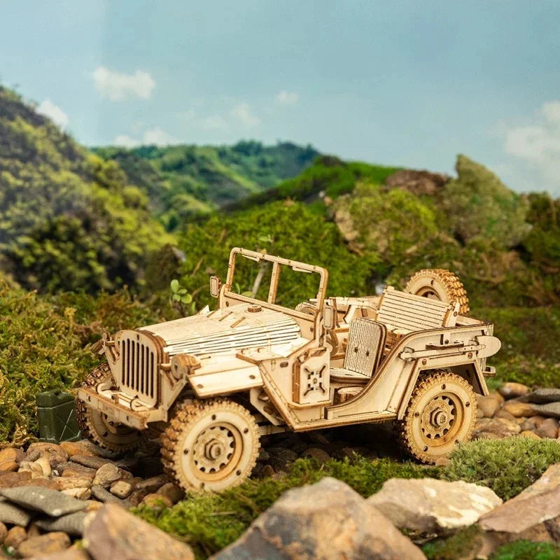 Wooden model jeep with detailed wheels and open top, displayed outdoors on mossy rocks