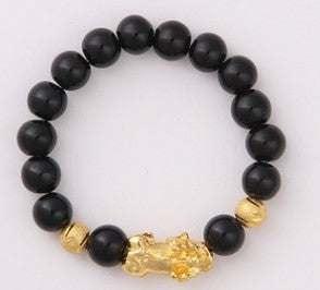 Black beaded bracelet with gold accents and gold animal charm, stretch fit