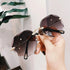 Hand holding oversized rimless sunglasses with dark gradient lenses and gold metal accents