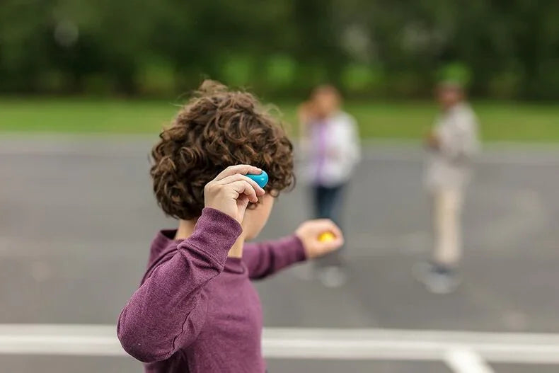 Child wearing long sleeve purple shirt, relaxed fit, playing outdoors on pavement.
