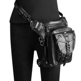 Black faux leather utility belt bag with silver hardware, worn over black skinny jeans