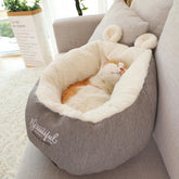 Cat sleeping in a plush, grey and white faux fur pet bed with ear-shaped accents