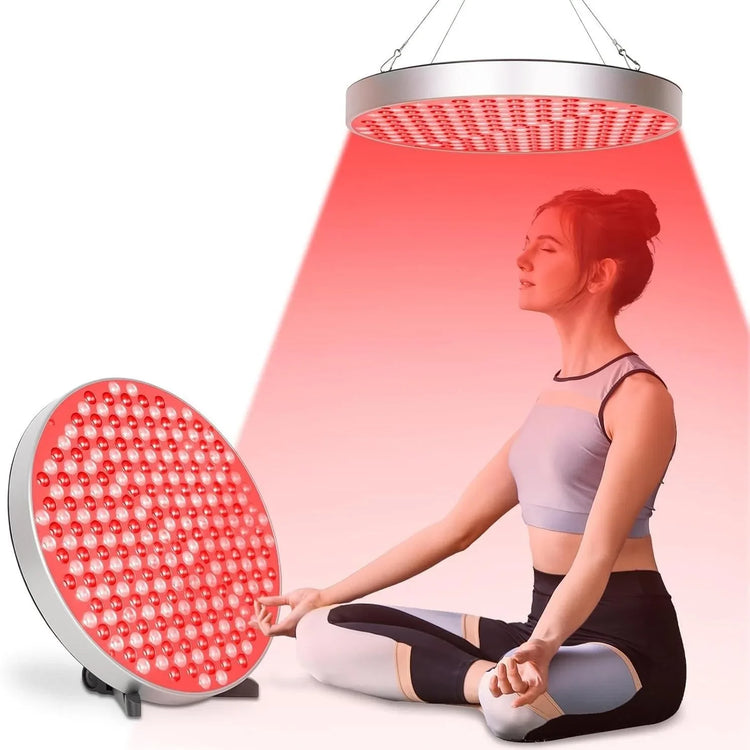 Woman in fitted athletic crop top and leggings meditating under red light therapy lamp