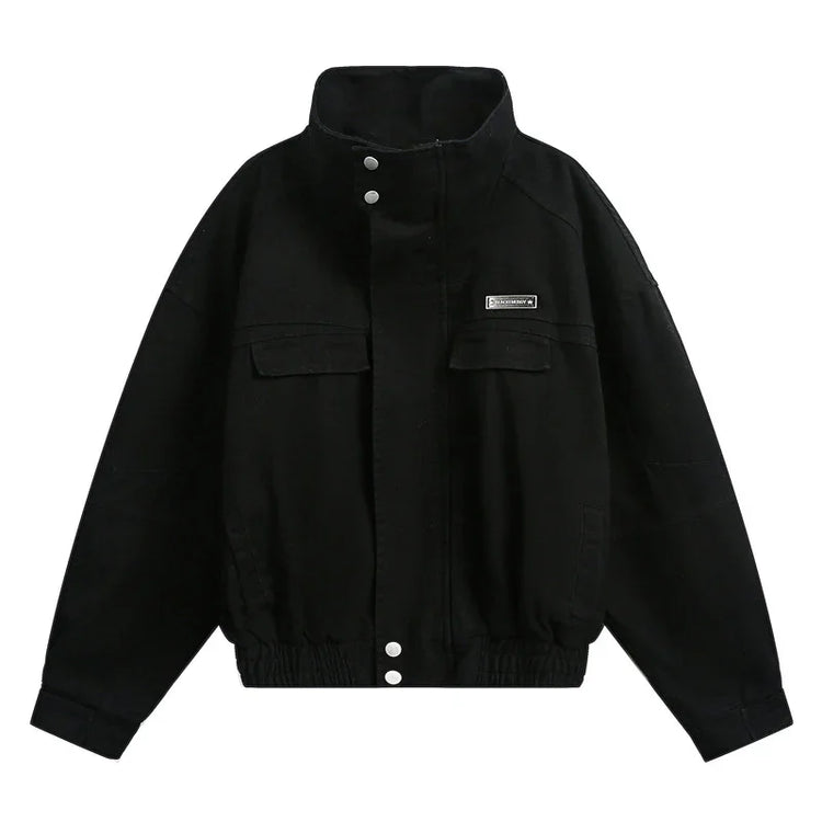 Black oversized streetwear jacket with high collar, snap buttons, chest pockets, and elastic hem.