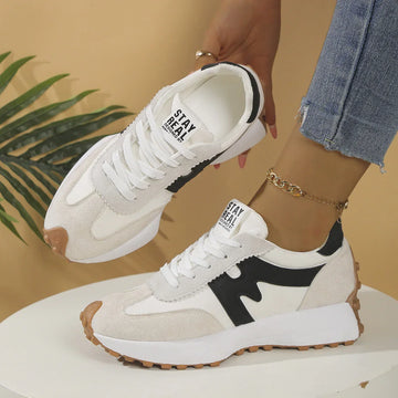 White and beige suede sneakers with black accents, gum sole, casual fit, styled with jeans.