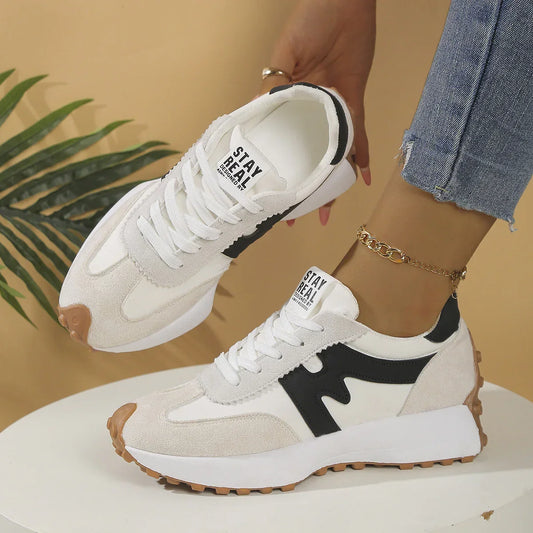 White and beige suede sneakers with black accents, gum sole, casual fit, styled with jeans.
